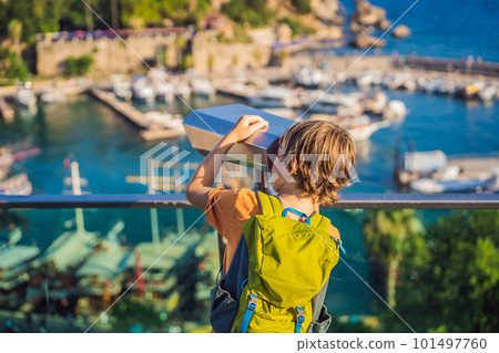 Boy tourist looks through binoculars in Old town Kaleici in Antalya. Turkiye. Panoramic view of Antalya Old Town port, Taurus mountains and Mediterrranean Sea, Turkey. Traveling with kids concept 101497760