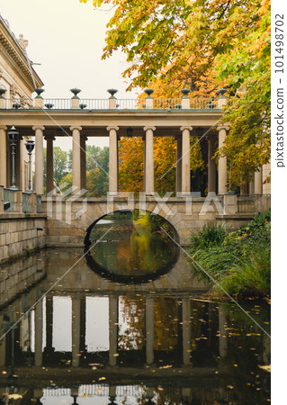 Baths classicist Palace on the Isle in Lazienki Park touristic place in Warsaw. Lazienki Royal Baths Park, Baroque columns Warsaw Poland. Colorful Autumn Foliage and Mirror Reflection on the Lake 101498702