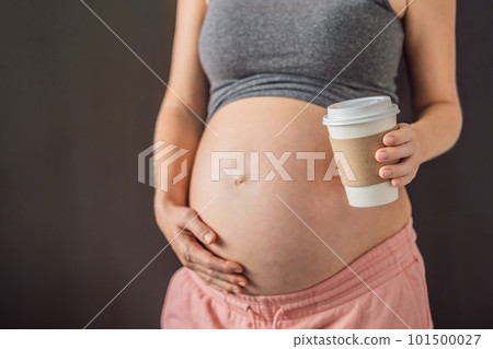 A pregnant woman holds a cup of coffee in her hands. Caffeine safety, myths about coffee during pregnancy concept A pregnant woman holds a cup of coffee in her hands. Caffeine safety, myths about coffee during pregnancy concept 101500027