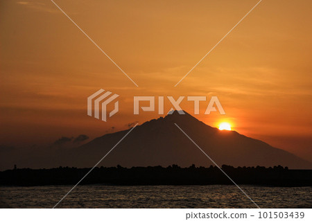 The sea dyed in the setting sun and the sun set in the shadow of the mountains 101503439