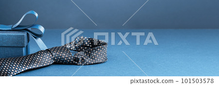 Happy Fathers Day background banner. Two blue gift boxes with ribbon bow and necktie on dark blue table. Monochrome. Gift delivery for him. Male fashion 101503578