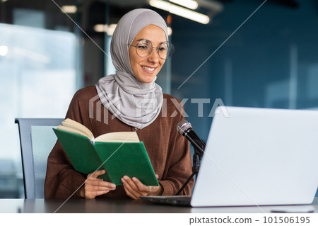 Young beautiful muslim woman in hijab working in modern office using professional microphone to record audio podcast reading religious book online radio. Young beautiful muslim woman in hijab working in modern office using professional microphone to record audio podcast reading religious book online radio. 101506195