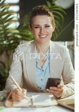 smiling business woman in light business suit in green office 101506968