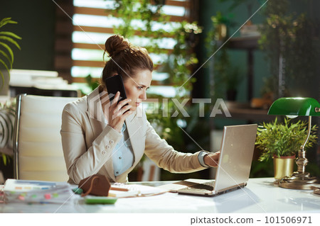 business woman in green office talking on phone 101506971