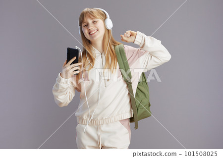 happy trendy pupil listening to music and using phone 101508025