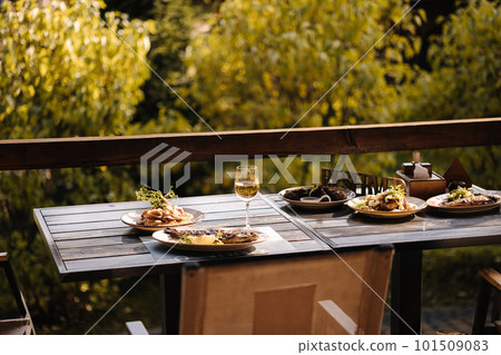 Dinner on summer terrace. Several dishes of fish and some meat in restaurant. Glasses with vine Dinner on summer terrace. Several dishes of fish and some meat in restaurant. Glasses with vine 101509083