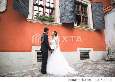 Gorgeous happy couple standing close to each other and looking in eyes at old city background, wedding photo, European city, wedding day in Lviv 101509290