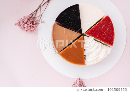 Top view of different pieces of cheesecake with different flavors on pink background with dried flowers 101509553