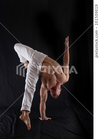 circus artist keeps balance on one hand isolated on a black background. Concept of individuality, creativity and self-confidence circus artist keeps balance on one hand isolated on a black background. Concept of individuality, creativity and self-confidence 101509819