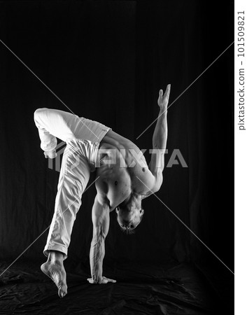circus artist keeps balance on one hand isolated on a black background. concept of handstand and calisthenic circus artist keeps balance on one hand isolated on a black background. concept of handstand and calisthenic 101509821