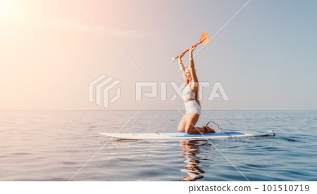 Woman sea sup. Close up portrait of happy young caucasian woman with long hair looking at camera and smiling. Cute woman portrait in bikini posing on sup board in the sea 101510719