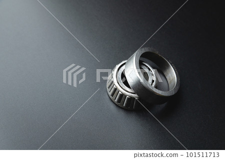 Tapered roller bearing close-up with copy space for your text. Spare mechanical part on a black background. 101511713