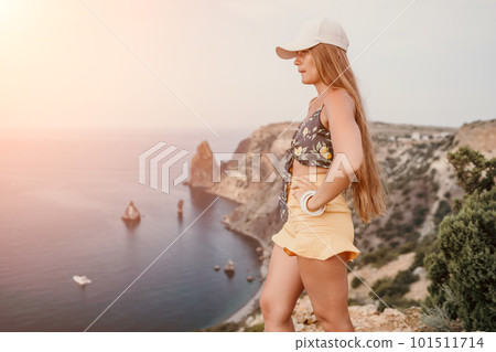Woman travel sea. Happy tourist taking picture outdoors for memories. Woman traveler looks at the edge of the cliff on the sea bay of mountains, sharing travel adventure journey Woman travel sea. Happy tourist taking picture outdoors for memories. Woman traveler looks at the edge of the cliff on the sea bay of mountains, sharing travel adventure journey 101511714