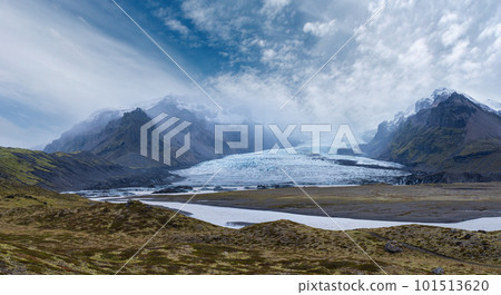 Glacier tongue slides from the Vatnajokull icecap or Vatna Glacier near subglacial Oraefajokull volcano, Iceland. Glacial lagoon with ice blocks and surrounding mountains. Glacier tongue slides from the Vatnajokull icecap or Vatna Glacier near subglacial Oraefajokull volcano, Iceland. Glacial lagoon with ice blocks and surrounding mountains. 101513620