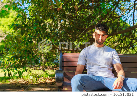 Indian man sitting on a park bench 101513821