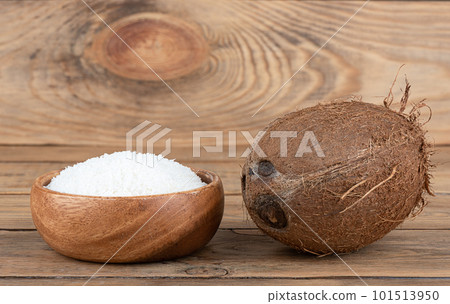 Whole coconut and coconut flakes in a wooden bowl on a wooden background. Whole coconut and coconut flakes in a wooden bowl on a wooden background. 101513950