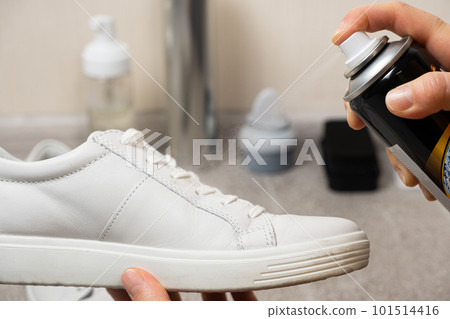 Applying a water-repellent hydrophobic spray to white women's sneakers. Protection of shoes from moisture, dirt and unpleasant odor. Applying a water-repellent hydrophobic spray to white women's sneakers. Protection of shoes from moisture, dirt and unpleasant odor. 101514416