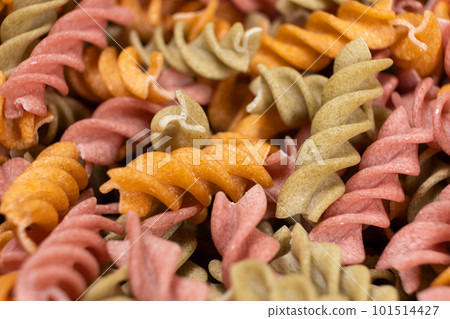 Rice vegetable pasta in the form of spirals, top view. Healthy rice pasta with tomatoes, celery, carrots and beets Rice vegetable pasta in the form of spirals, top view. Healthy rice pasta with tomatoes, celery, carrots and beets 101514427
