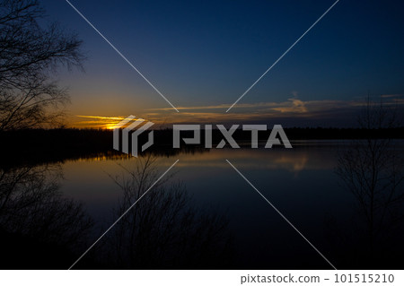 Dramatic sunset over a forest lake 101515210