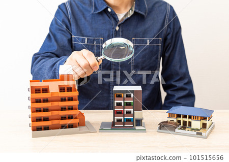 A man observing a model house with a magnifying glass A man observing a model house with a magnifying glass 101515656