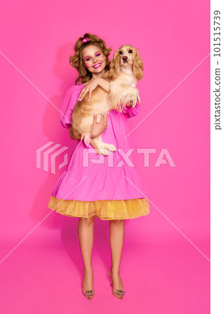 Portrait of stunning, young, beautiful woman wearing like sweet doll over pink studio background. Lady with cute dog Portrait of stunning, young, beautiful woman wearing like sweet doll over pink studio background. Lady with cute dog 101515739