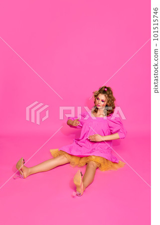 One beautiful blond woman, girl with bright makeup wearing doll dress and heels posing over pink studio background. Blank face 101515746