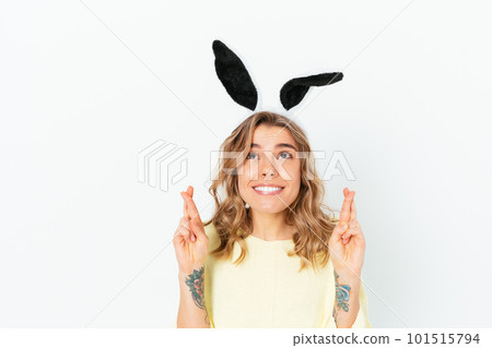 Portrait hopeful young woman wearing rabbit ears crossed fingers Portrait hopeful young woman wearing rabbit ears crossed fingers 101515794