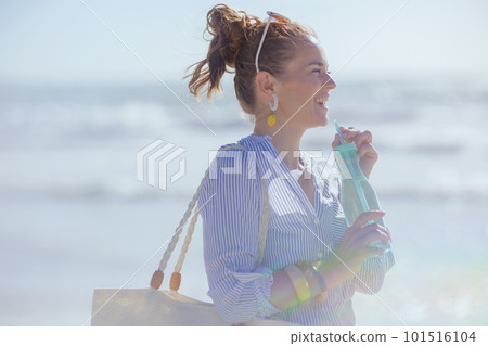 happy stylish woman with white straw bag and drink at beach happy stylish woman with white straw bag and drink at beach 101516104