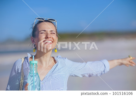 happy modern woman with drink rejoicing at beach 101516106