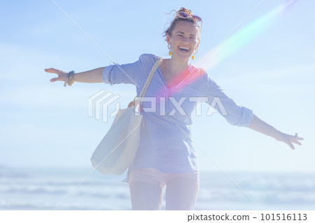 smiling stylish 40 years old woman rejoicing at beach 101516113