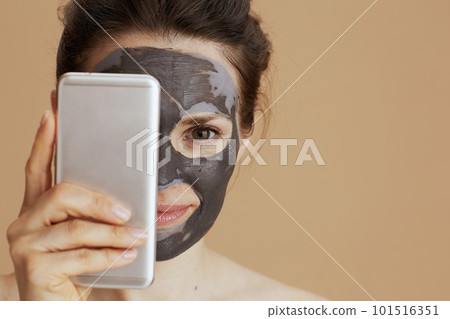 modern 40 years old woman with cosmetic mask using smartphone 101516351