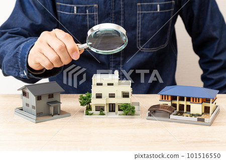 A man observing a model house with a magnifying glass 101516550