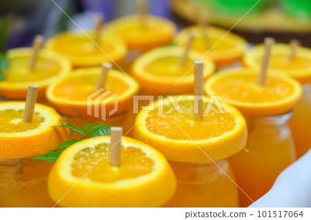 Glass of orange juice, slice of fresh orange on top with paper straw prepared for party. Glass of orange juice, slice of fresh orange on top with paper straw prepared for party. 101517064