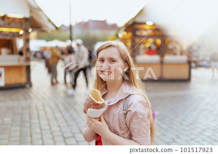 modern girl in pink jacket at fair in city eating trdelnik 101517923