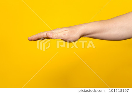 Strong man's arm with palm outstretched upside down isolated on yellow background. Strong man's arm with palm outstretched upside down isolated on yellow background. 101518197