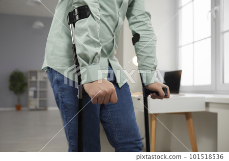 Young man with a broken leg walks with crutches during a recovery period at home 101518536