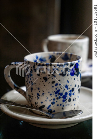 White coffee cup with blue spots on a saucer with a spoon on a wooden table White coffee cup with blue spots on a saucer with a spoon on a wooden table 101518691