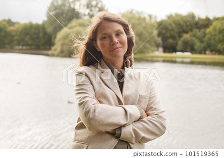 Cute smiling woman with brown hair looking at camera outdoors 101519365