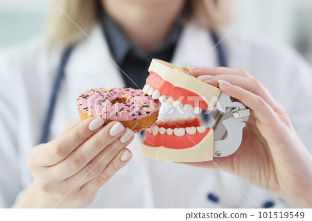 Woman imitates biting of sweet donut with human jaws model 101519549