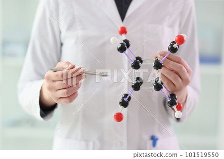 Woman in lab coat demonstrates molecule model in hands 101519550
