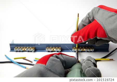 Electrician in protective gloves fixes electric cables with a screwdriver Electrician in protective gloves fixes electric cables with a screwdriver 101519724