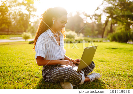 Young woman freelancer sitting on green grass with laptop. Education online. 101519928
