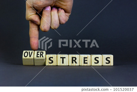 Over stress symbol. Psychologist turns wooden cubes and changes the concept word Stress to Over stress. Beautiful grey table grey background, copy space. Psychlogical over stress concept. 101520037