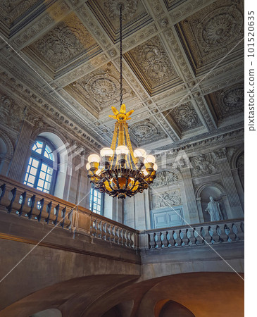 Architectural details of a ornate staircase hall with a glowing vintage chandelier hanging from ceiling at Versailles Palace, France Architectural details of a ornate staircase hall with a glowing vintage chandelier hanging from ceiling at Versailles Palace, France 101520635