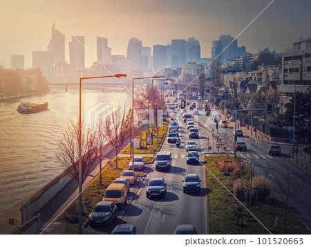 Busy traffic on highway and city streets creating high pollution and smog. Urban sunset view across Seine river to La Defense metropolitan district, Paris, France 101520663