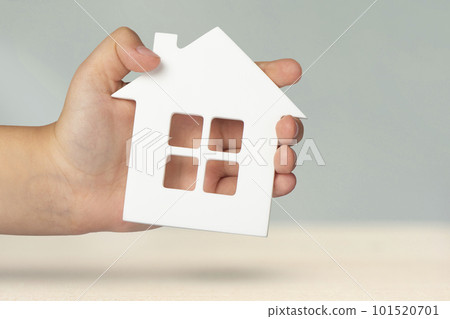 Real estate insurance. Model of a white house in hands on a gray blurred background. Insure a house or apartment, the concept of insurance services, with copy space Real estate insurance. Model of a white house in hands on a gray blurred background. Insure a house or apartment, the concept of insurance services, with copy space 101520701