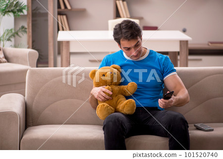 Young man with toy bear at home 101520740