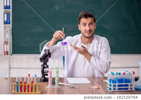 Young male chemist in front of green board 101520784