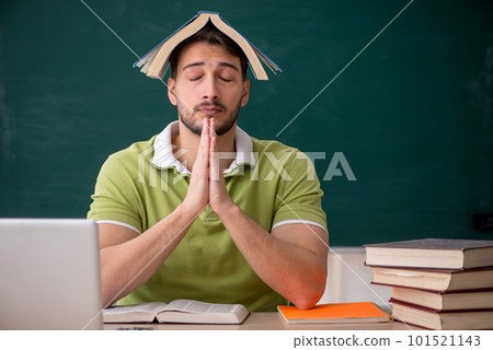 Young male student sitting in front of green board Young male student sitting in front of green board 101521143