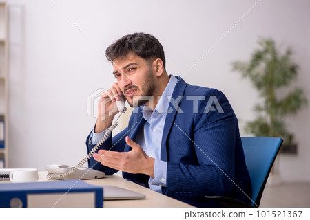 Young male employee sitting at workplace Young male employee sitting at workplace 101521367